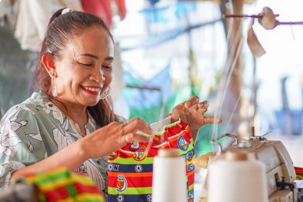 Ning sewing something together, smiling.