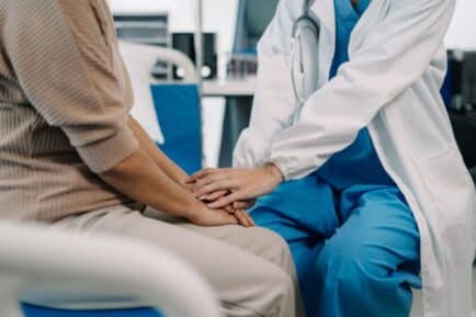 Doctor placing hand on female patient's, reassuring.